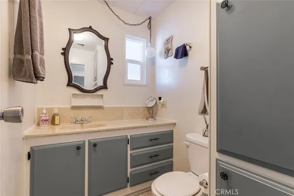 a bathroom with a toilet sink vanity and mirror