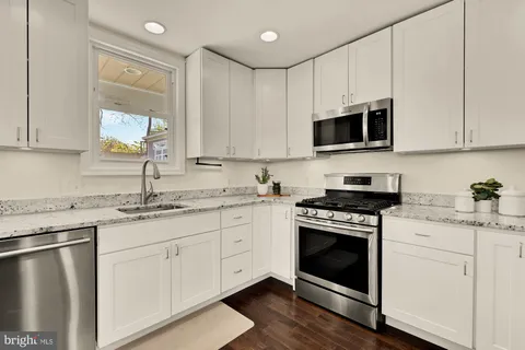 a kitchen with granite countertop white cabinets sink and appliances