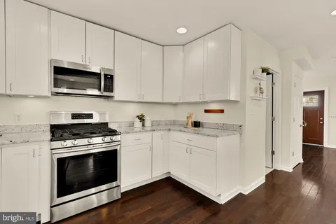 a kitchen with cabinets stainless steel appliances a sink and wooden floor