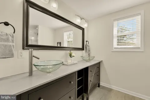 a bathroom with a sink a mirror and wooden floor