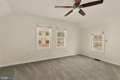 an empty room with windows and fan