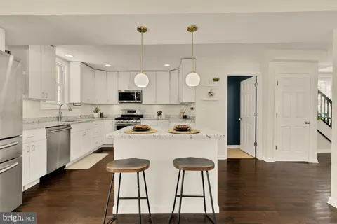 a kitchen with stainless steel appliances kitchen island granite countertop a stove a sink dishwasher and a refrigerator with wooden floor