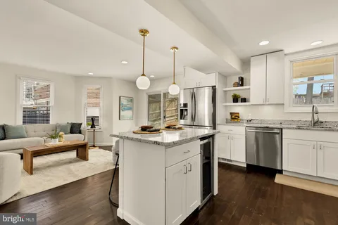 a kitchen with stainless steel appliances granite countertop a stove a sink dishwasher a refrigerator and white cabinets with wooden floor