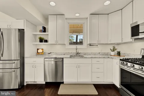 a kitchen with granite countertop white cabinets and stainless steel appliances