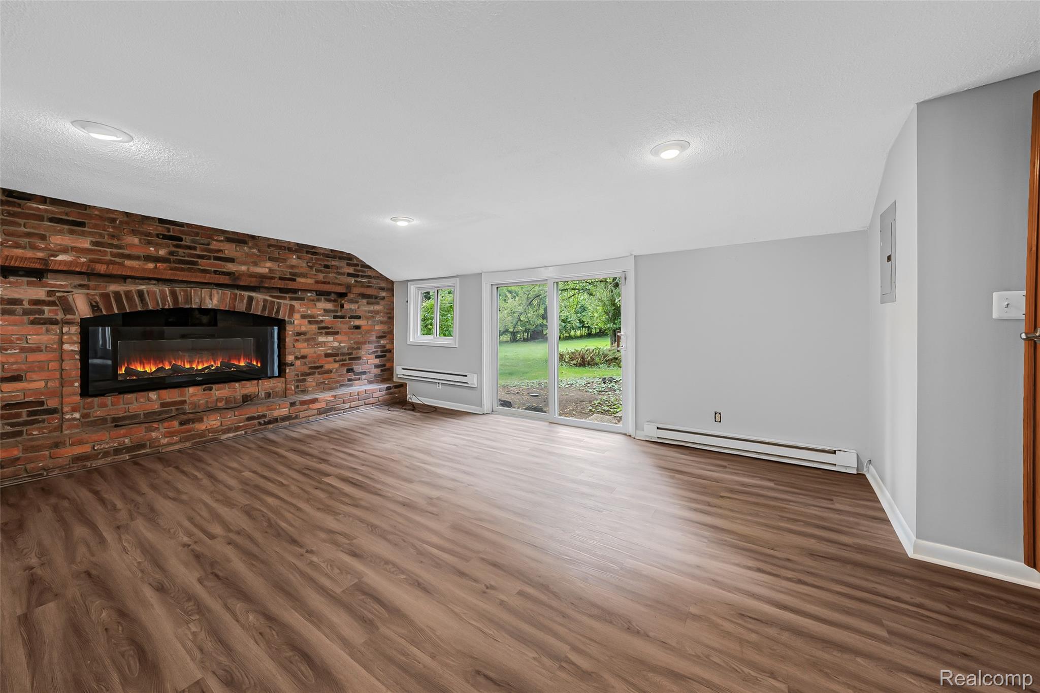 2329 Rutherford Road Bloomfield Hills, MI 48302 - Photo 27 of 46 Brick accent wall with an integrated electric fireplace, wood-finish flooring, recessed ceiling lighting, and sliding glass door access to the exterior
