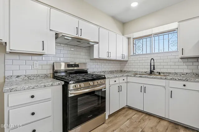 a kitchen with granite countertop a stove sink and cabinets