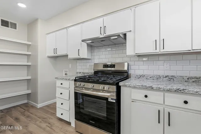 a kitchen with stainless steel appliances granite countertop a stove and a white cabinets
