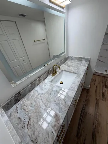 a bathroom with a granite countertop sink and a mirror