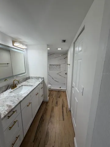 a spacious bathroom with a granite countertop sink a mirror and a shower