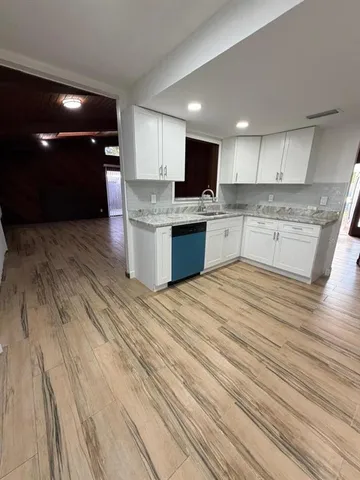 a large kitchen with kitchen island a sink dishwasher a stove and a refrigerator with wooden floor