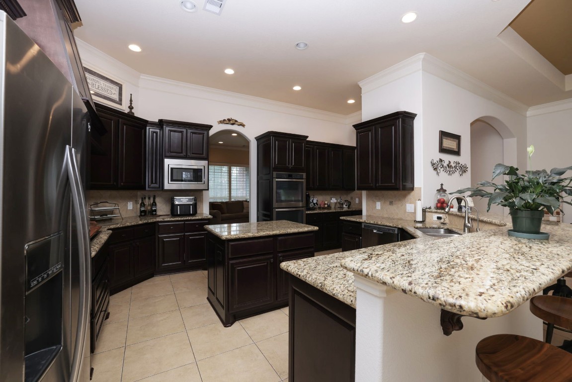 1547 Ruby Drive Willis, TX 77378 - Photo 16 of 45 a kitchen with granite countertop kitchen island stainless steel appliances a sink and a refrigerator