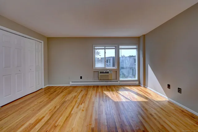 a view of empty room with window and wooden floor