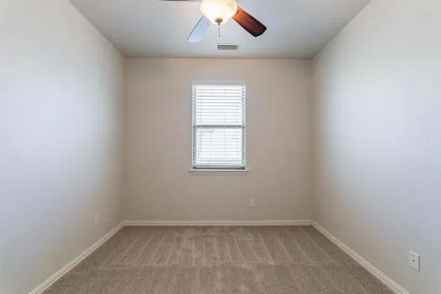 an empty room with chandelier fan