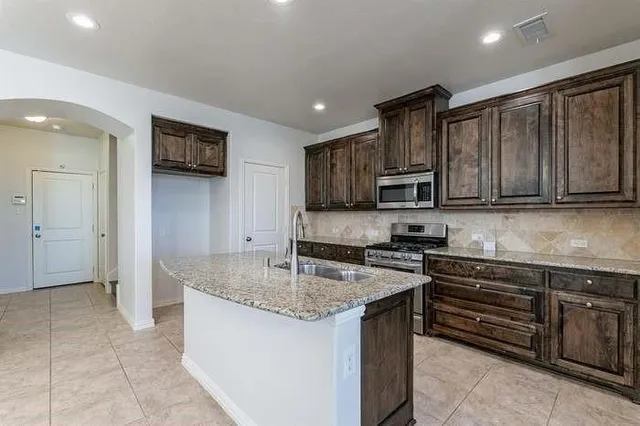 a kitchen with granite countertop a sink and white cabinets