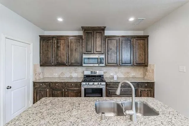 a kitchen with a refrigerator and a stove top oven