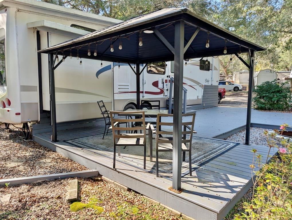 14131 Northeast 253rd Ave Road Salt Springs, FL 32134 - Photo 13 of 26 a view of a patio with table and chairs under an umbrella with a barbeque grill and wooden floor
