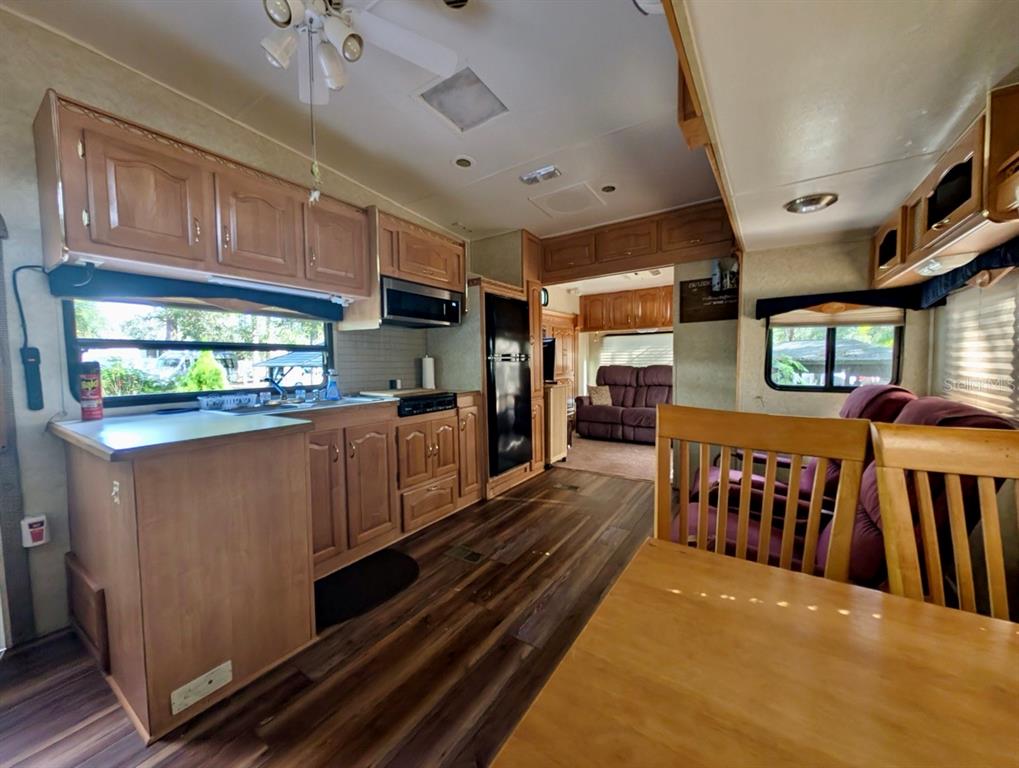 14131 Northeast 253rd Ave Road Salt Springs, FL 32134 - Photo 9 of 26 a open kitchen with stainless steel appliances granite countertop a refrigerator a sink dishwasher a stove and white countertops with wooden floor