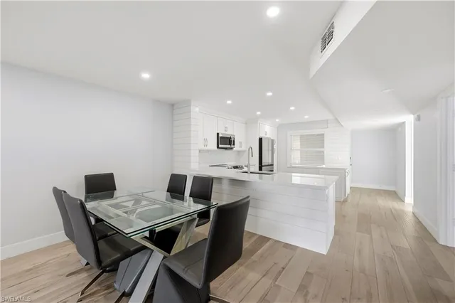 a living room with stainless steel appliances furniture and wooden floor