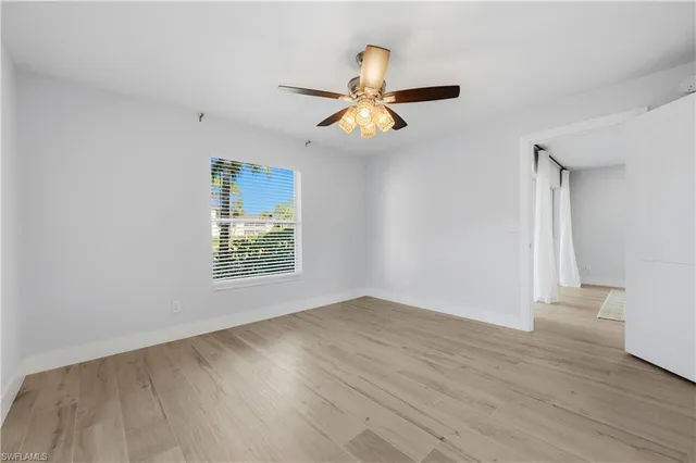 an empty room with wooden floor a ceiling fan and window