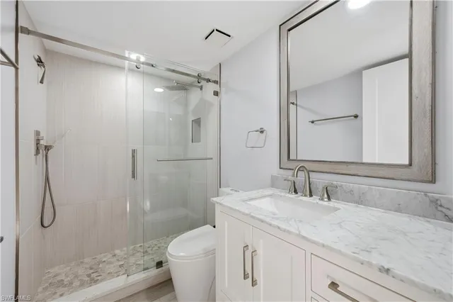 a bathroom with a granite countertop shower sink vanity and toilet