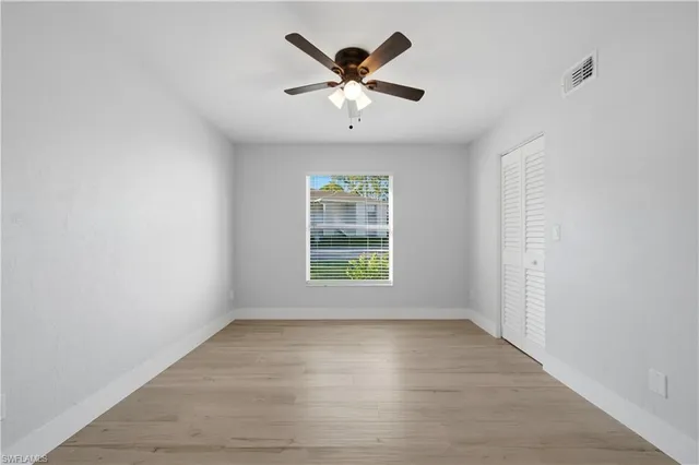an empty room with window and ceiling fan