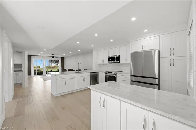 a kitchen with stainless steel appliances kitchen island granite countertop a refrigerator and a stove top oven