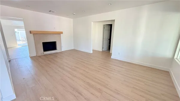 a view of an empty room with wooden floor and a fireplace