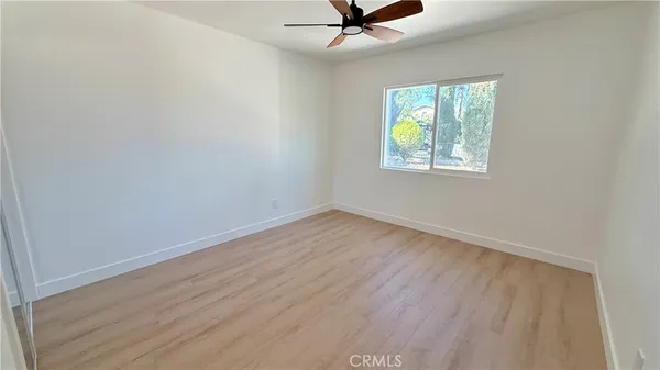 an empty room with wooden floor and a ceiling fan