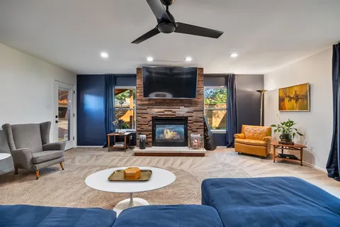 a living room with furniture a fireplace a flat screen tv and a large window