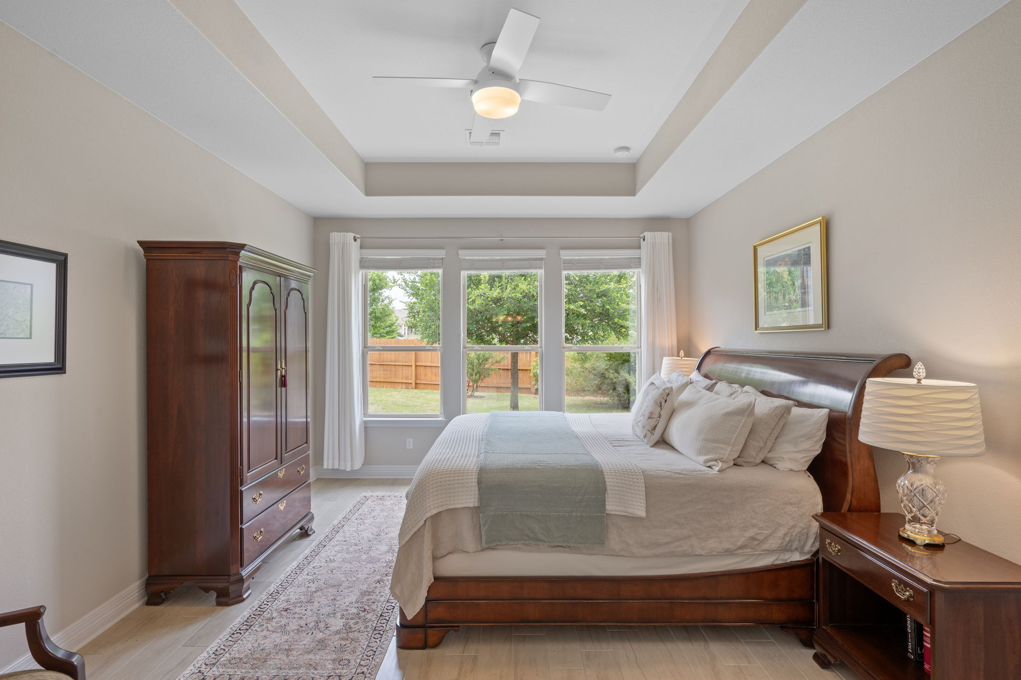 408 Bell Boot Pass Georgetown, TX 78626 - Photo 14 of 40 This bedroom offers a tray ceiling with a ceiling fan, light-toned flooring, and large windows providing views of the outdoor space