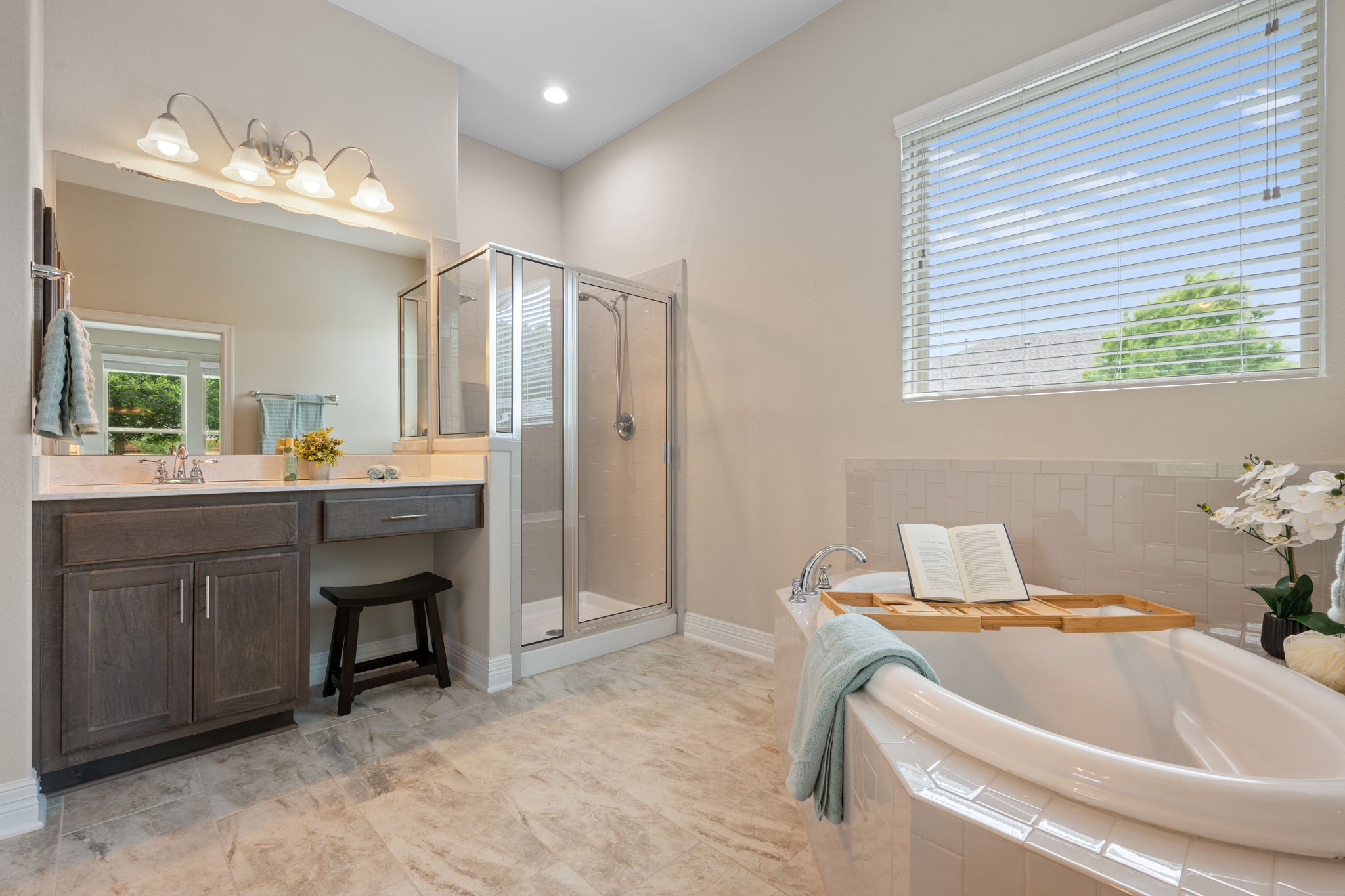 408 Bell Boot Pass Georgetown, TX 78626 - Photo 16 of 40 Well-appointed bathroom featuring a spacious soaking tub with tiled surround, a separate glass-enclosed shower, a double vanity with a large mirror, and tiled flooring
