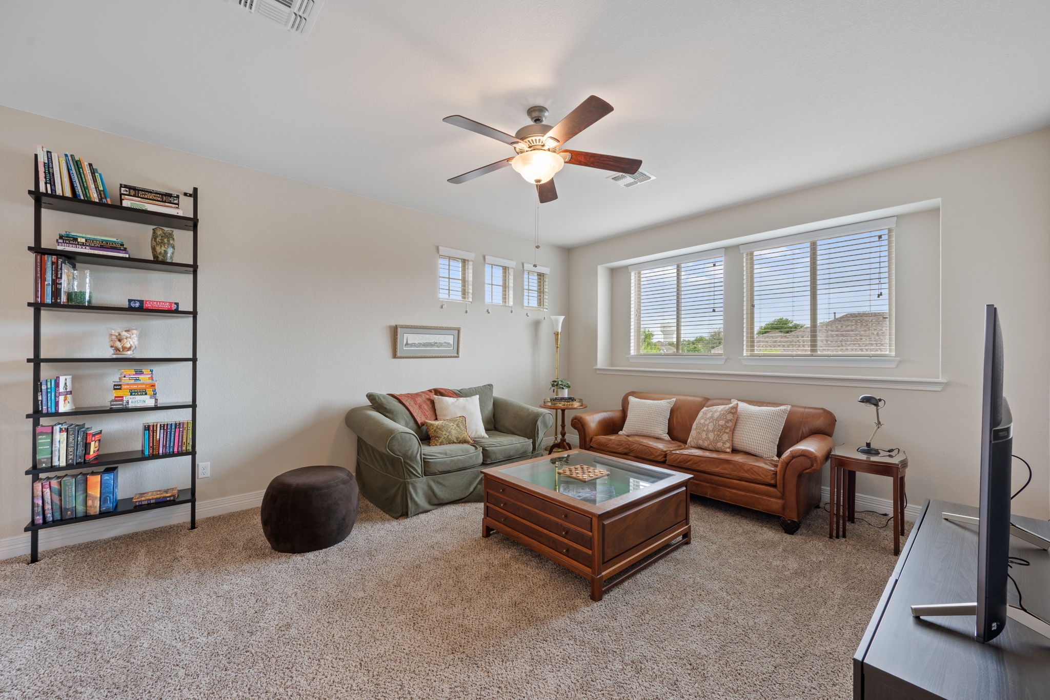 408 Bell Boot Pass Georgetown, TX 78626 - Photo 27 of 40 Spacious living area featuring neutral carpeting, a ceiling fan with integrated lighting, and large windows providing natural light