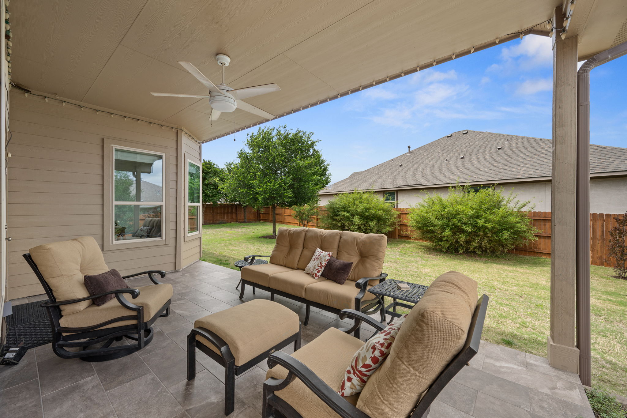 408 Bell Boot Pass Georgetown, TX 78626 - Photo 31 of 40 The property features a covered patio with a ceiling fan, overlooking a fenced yard with established bushes and a tree