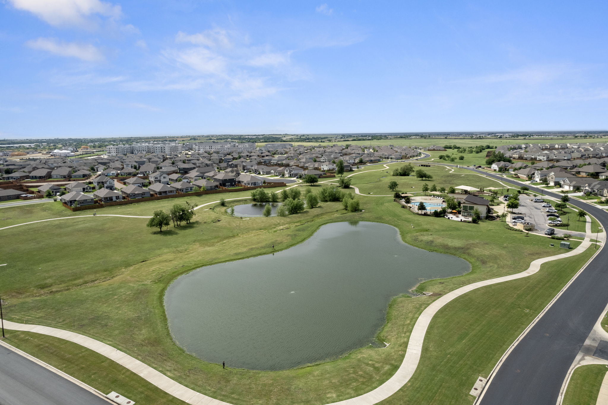 408 Bell Boot Pass Georgetown, TX 78626 - Photo 39 of 40 Aerial view showcasing the property's surrounding environment, featuring a large pond, expansive green spaces with walking paths, and a community pool area