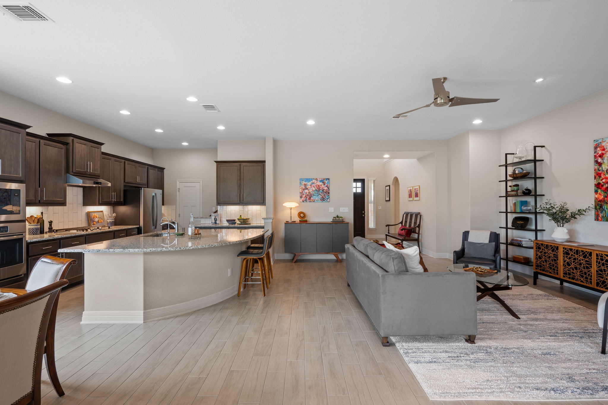 408 Bell Boot Pass Georgetown, TX 78626 - Photo 9 of 40 Open-concept living space featuring light-toned flooring, a kitchen with dark cabinetry, stainless steel appliances, and a kitchen island with a granite countertop