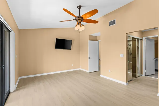 an empty room with closet and a ceiling fan