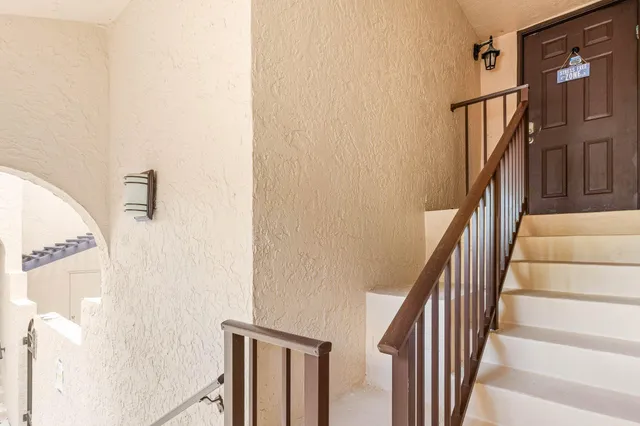 a view of staircase with lots of frames on wall and wooden door