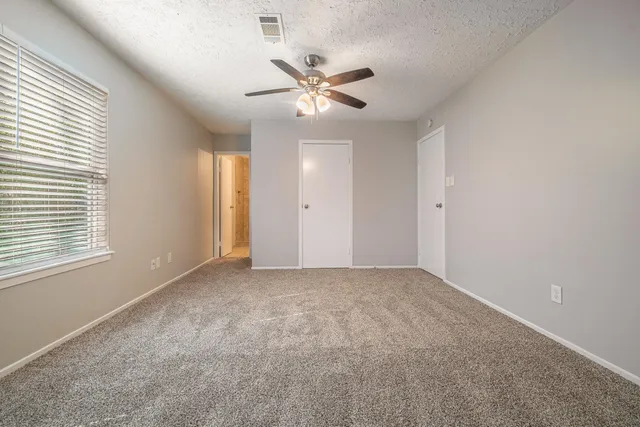 a view of an empty room with a ceiling fan and window