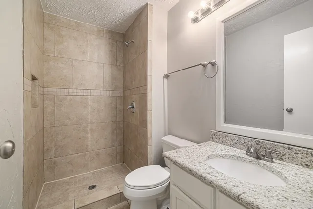 a bathroom with a granite countertop sink toilet mirror and shower