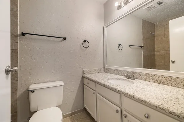 a bathroom with a granite countertop sink toilet and shower