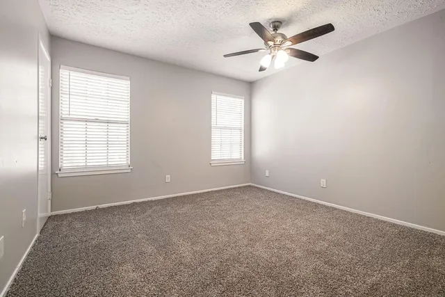 an empty room with windows and ceiling fan
