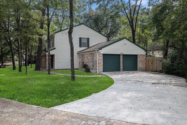 a view of a yard in front of a house with plants and large trees