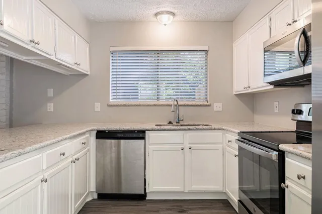 a kitchen with stainless steel appliances granite countertop a sink stove and cabinets