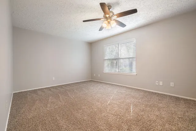 an empty room with chandelier fan and windows