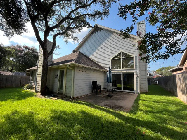 a view of a house with a yard and a large tree