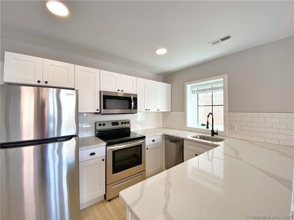 a kitchen with granite countertop a refrigerator stove and microwave