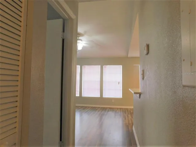 a view of an empty room with wooden floor and a window