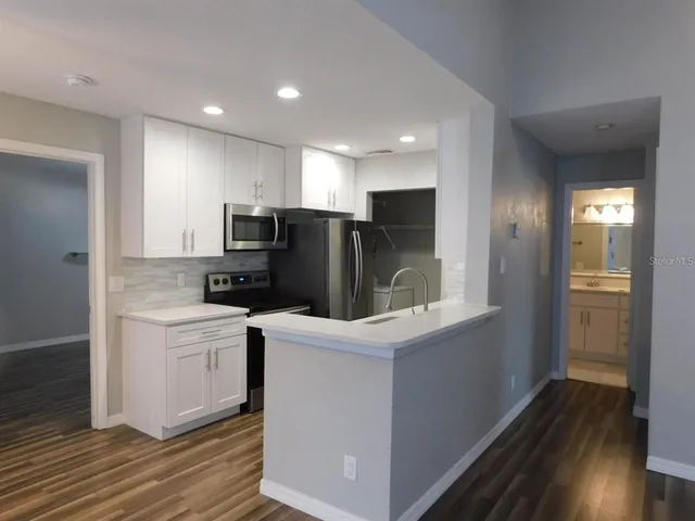 a kitchen with a sink a refrigerator and wooden floor