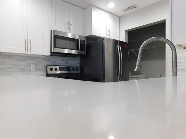 a kitchen with stainless steel appliances granite countertop a refrigerator a stove a microwave and a sink