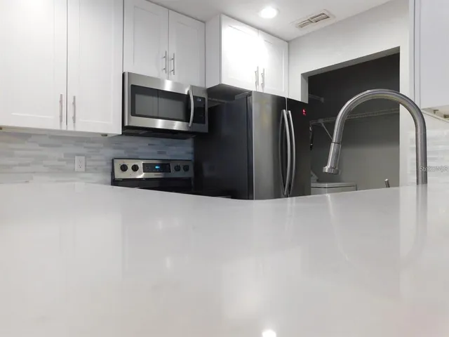 a kitchen with stainless steel appliances granite countertop a refrigerator a stove a microwave and a sink